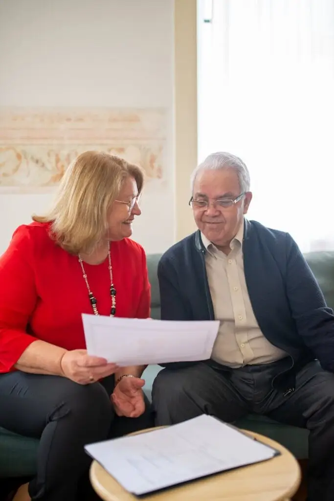 Senior couple consulting on pension options, smiling on a sofa, discussing documents.